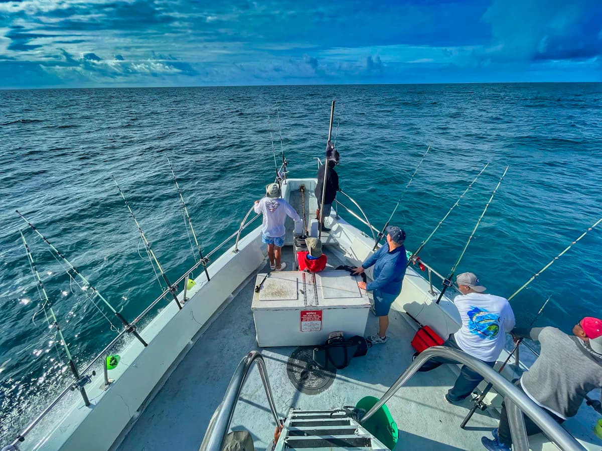 The deck of a charter fishing boat with rods out and anglers fishing offshore